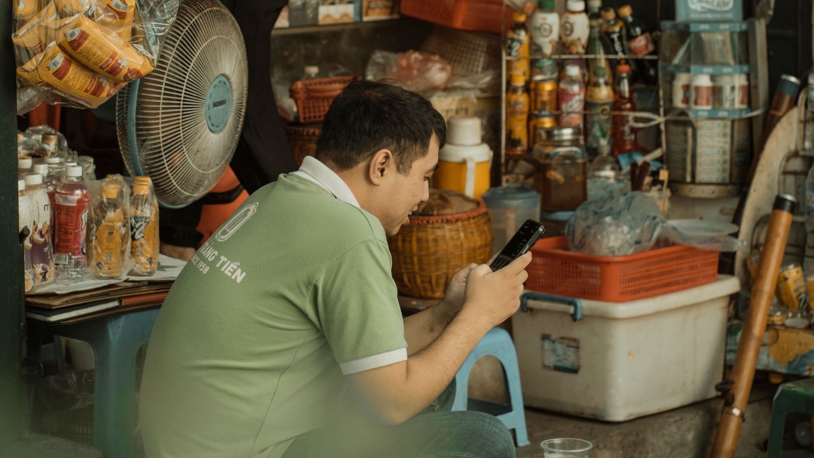 Pemilik warung membuka ponsel di pagi hari sebelum toko ramai