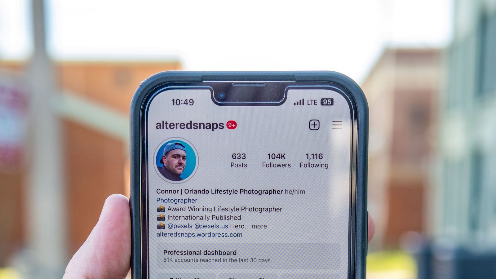 Tangan memegang ponsel yang menampilkan halaman profil Instagram beserta panel Professional dashboard