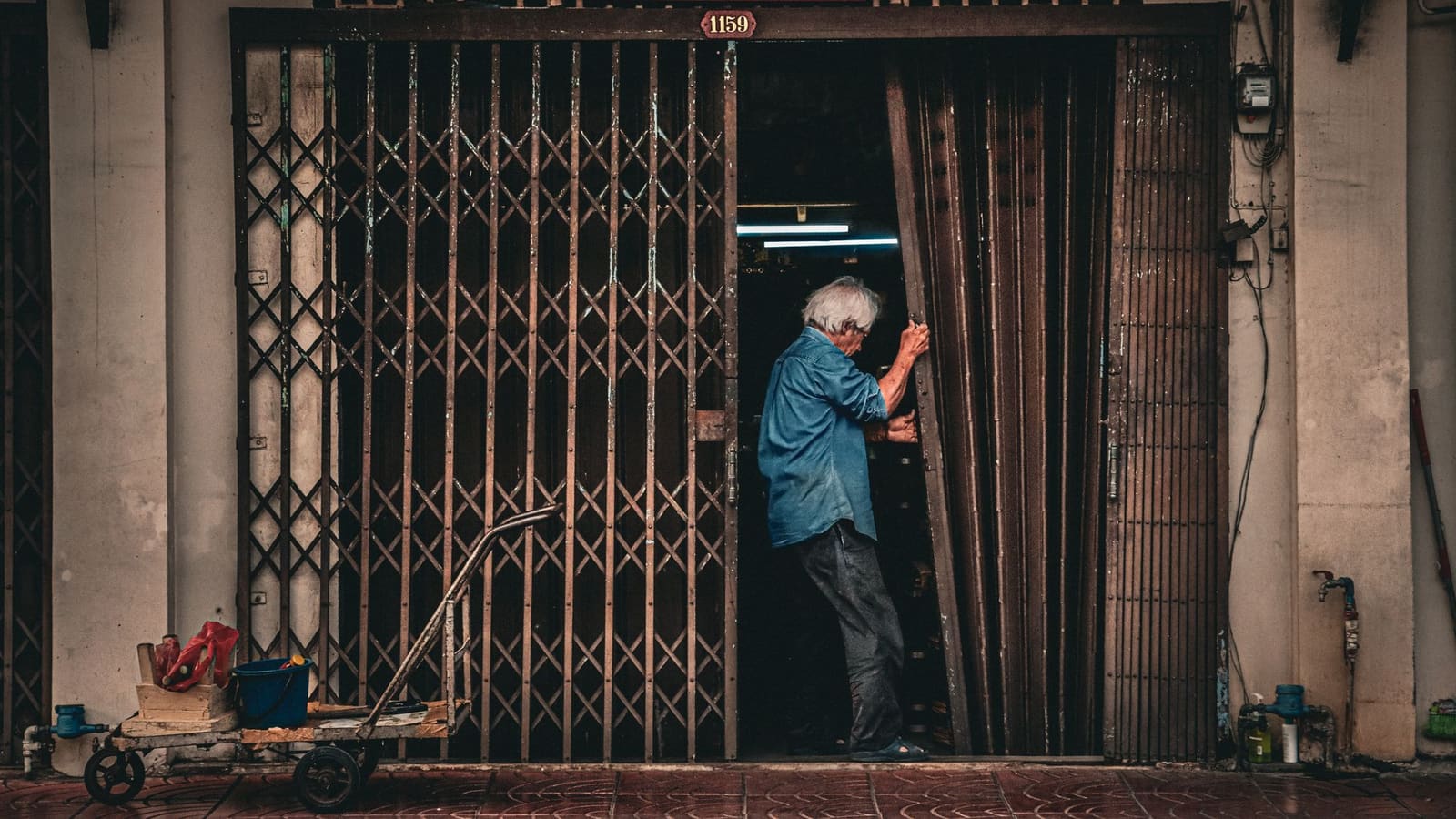 Pemilik toko menutup pintu besi tokonya