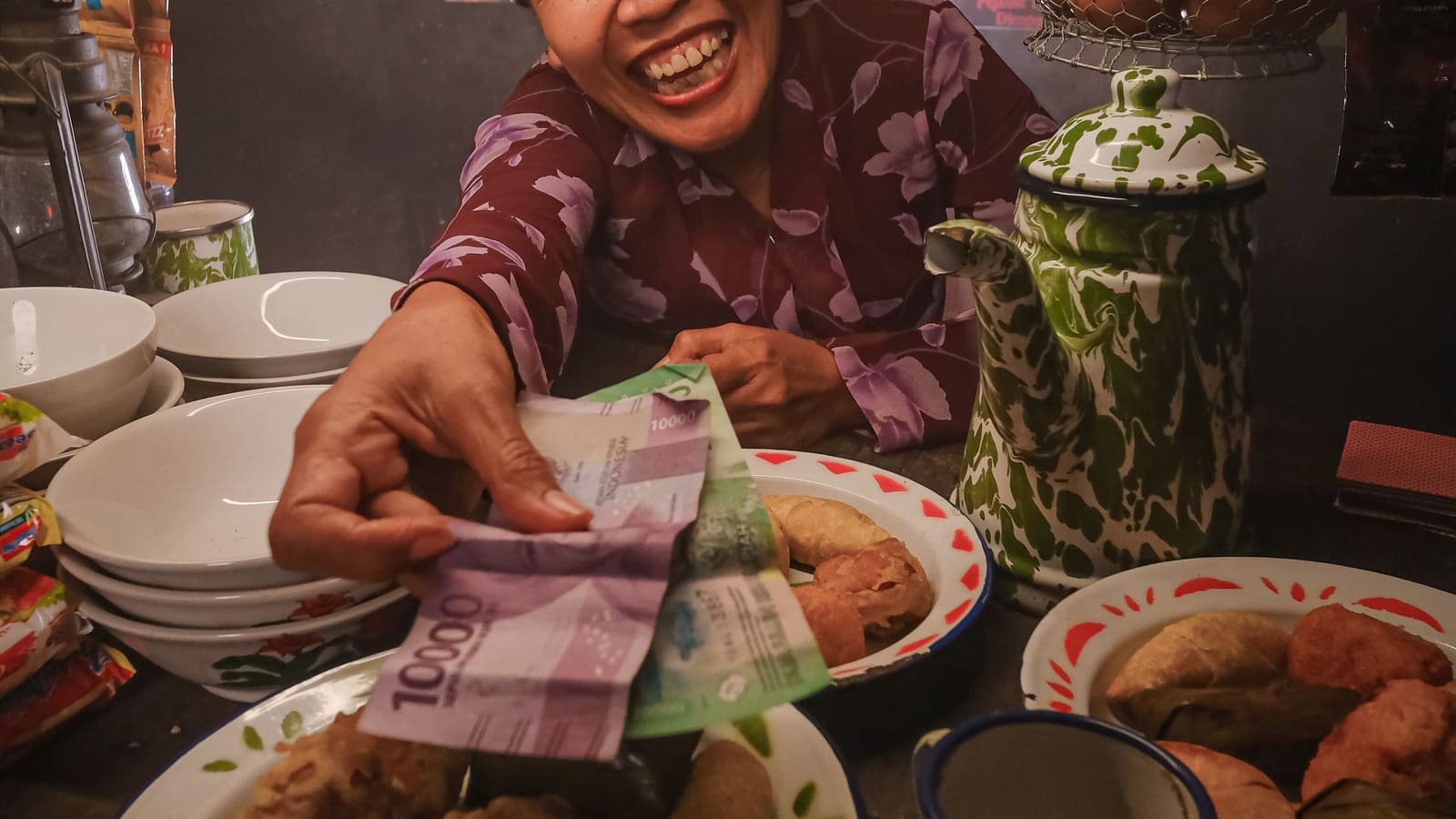 Pemilik warung menerima uang rupiah dari pembeli