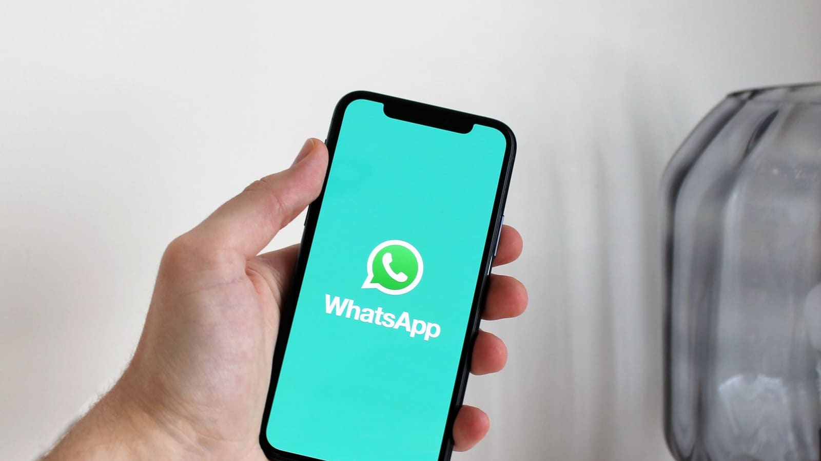 Tangan memegang ponsel yang menampilkan WhatsApp